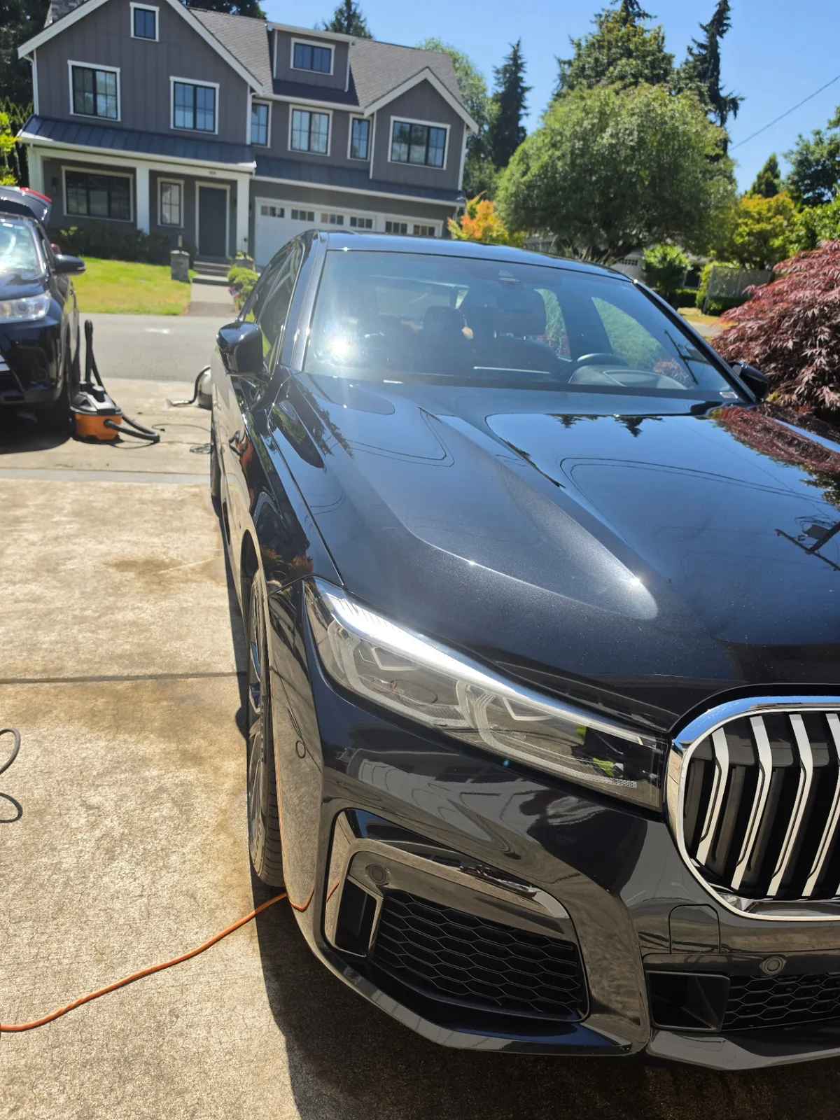 Black BMW 740i luxury sedan front quarter exterior with glossy finish after detailing