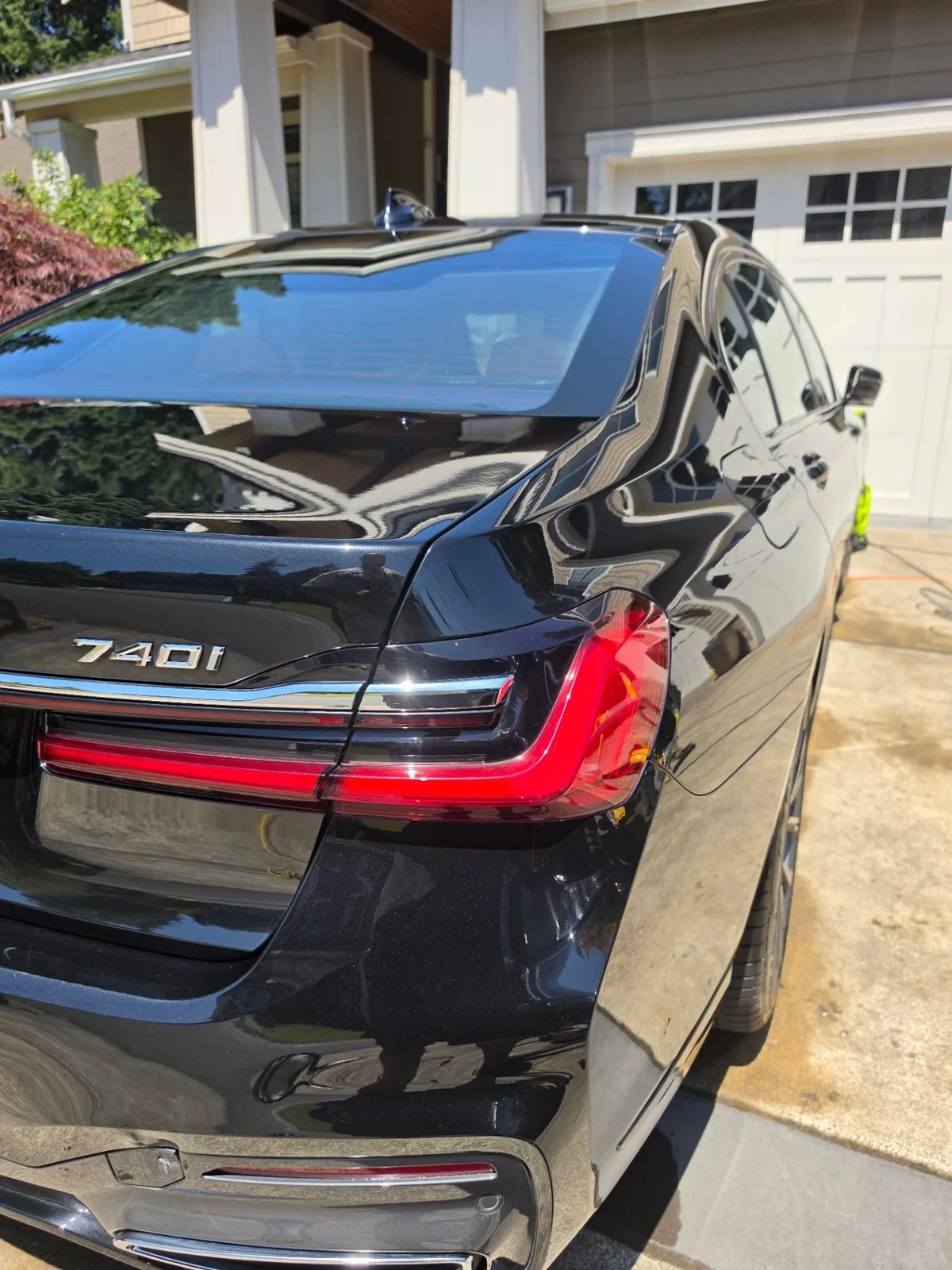 Black BMW 740i luxury sedan rear quarter exterior with reflective paint after detailing