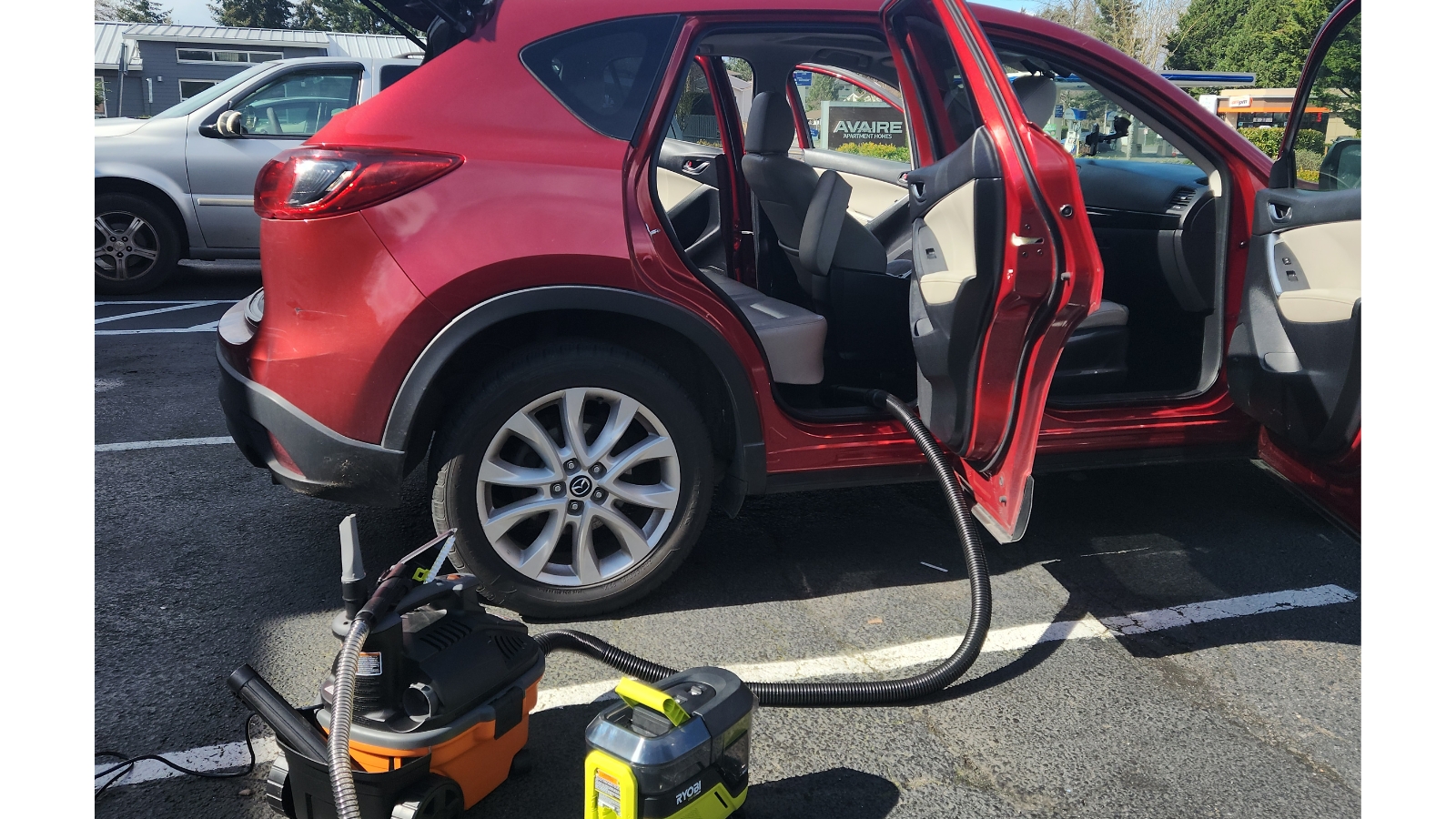 Red SUV being detailed with vacuum equipment
